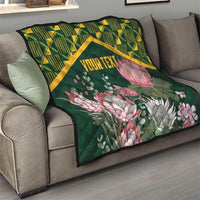 Green quilt with yellow kente border, pink protea flowers, and “YOUR TEXT” on couch