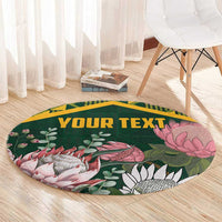 Green round rug with gold border, protea and fish illustrations, and YOUR TEXT lettering