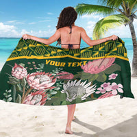 Green protea floral sarong with yellow kente pattern top band and custom text, back view