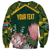 Green unisex sweatshirt with Kente-pattern sleeves and floral protea graphic, “YOUR TEXT”