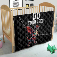 Black quilted blanket with Welsh dragon mascot and custom text, near baby crib