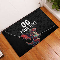 Black rubber doormat on wood floor with Welsh dragon mascot and custom text