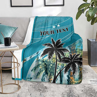 Personalized blue blanket with coconut palms and 'YOUR TEXT' on a gray sofa