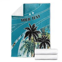 Personalized blue blanket with coconut palm print and 'YOUR TEXT', stacked with white towels