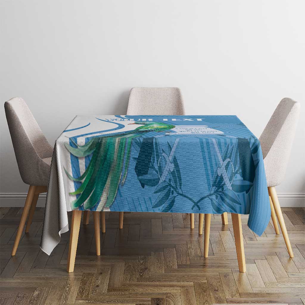 Blue tablecloth with tropical leaf and bird design on a dining table with chairs.