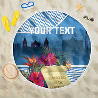 Blue round beach blanket with white fringe, tropical flowers, and skyline over checkered bands