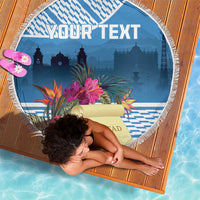 Blue round beach blanket with white fringe, tropical flowers, and skyline design with scroll