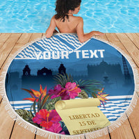 Blue round beach blanket with white fringe, tropical flowers, and “Libertad” scroll design