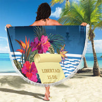 Blue round beach blanket with white fringe, tropical floral artwork and “Libertad 15 De Septi”