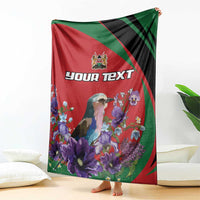 Personalized blanket draped: red-green-black design with bird, purple flowers, and custom text