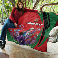 Personalized quilt draped over couch with red-and-green swirl, purple flowers, and “YOUR TEXT”
