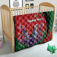 Personalized quilt in a crib with red-and-green swirl, purple flowers, and “YOUR TEXT”