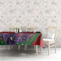 Purple and red floral tablecloth with green accents on dining table with chairs