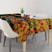 Black kente-pattern tablecloth with coat of arms, draped on dining table.