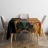Black kente-pattern tablecloth with coat of arms and 'HARAMBEE' text, draped on table.