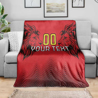 Red rugby blanket on gray sofa with lion head artwork, “00 YOUR TEXT,” and zigzag pattern