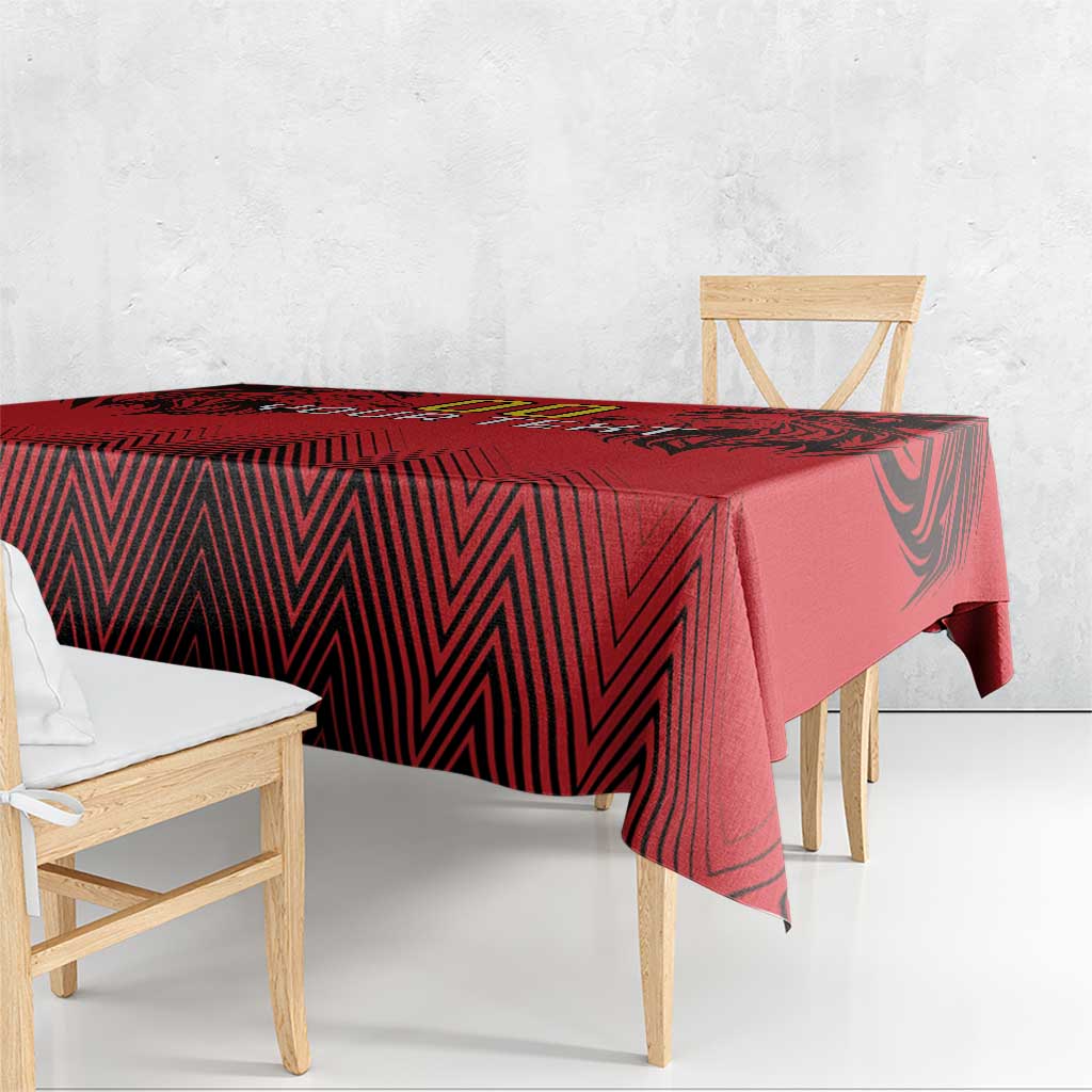 Red and black tablecloth draped over a bench table with geometric zigzag design.