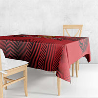 Red and black tablecloth draped over a bench table with geometric zigzag design.