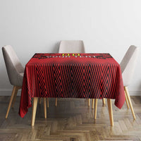 Red and black tablecloth with lion motifs and zigzag lines on a small dining table.