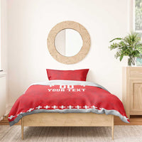 Red duvet cover set on bed with two pillows; white “DO YOUR TEXT” and rugby cross trim.