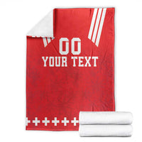 Red rugby blanket with 'YOUR TEXT' on display beside folded white towels