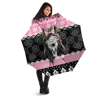 Pink and black umbrella with Mari Lwyd skull, Celtic knots, held open by a person