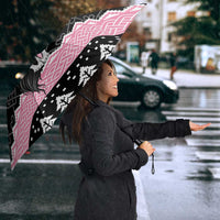 Pink and black umbrella with Mari Lwyd skull and Celtic knot pattern, seen from side angle