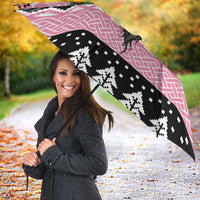 Pink and black umbrella with Mari Lwyd skull and Celtic knot design, open and angled