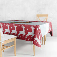 Red Christmas tablecloth with white reindeer and stars pattern draped over a bench