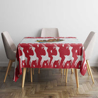 Red Christmas tablecloth with white reindeer and star pattern across a table