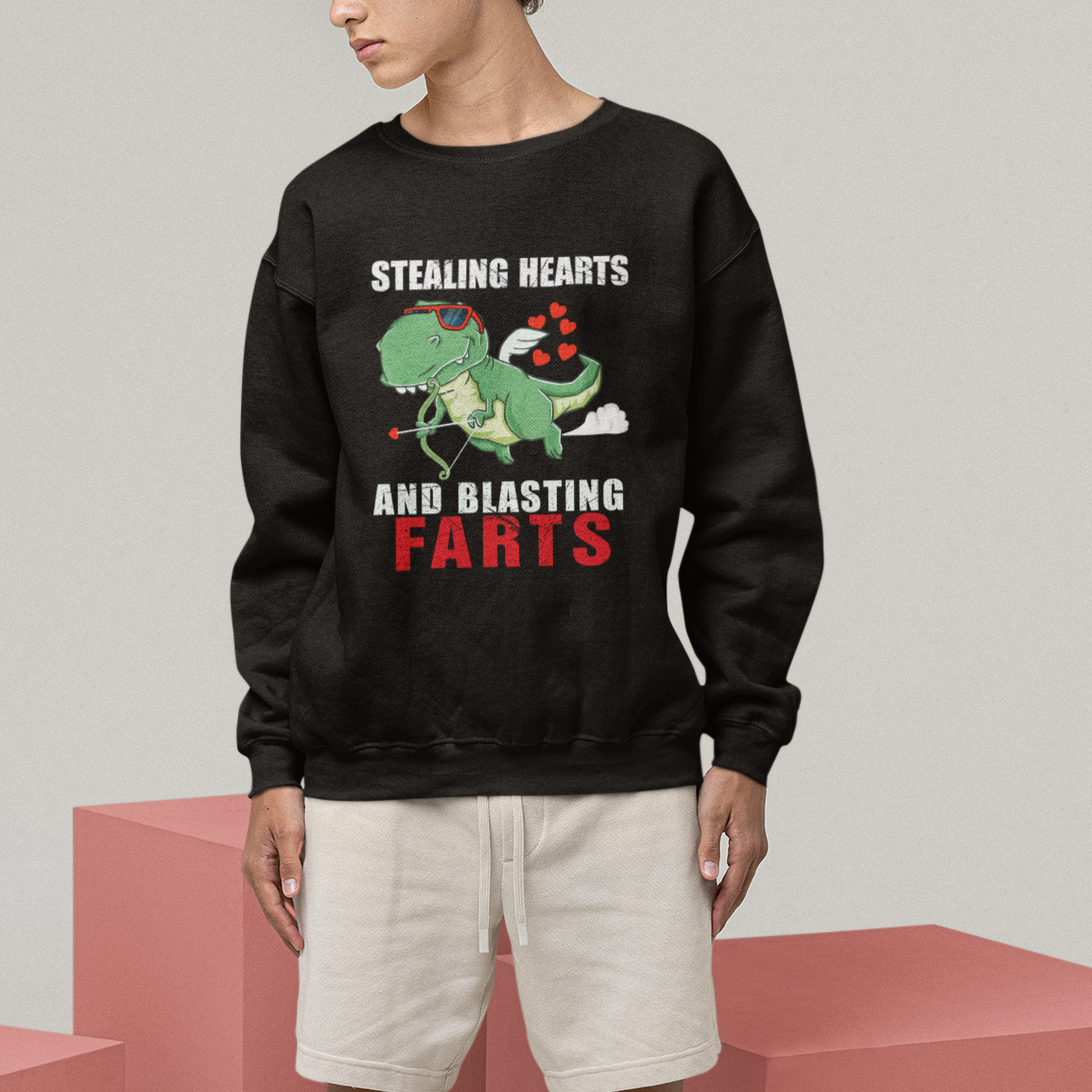 Black sweatshirt worn by person, featuring green dinosaur cupid “Stealing Hearts and Blasting Farts” print