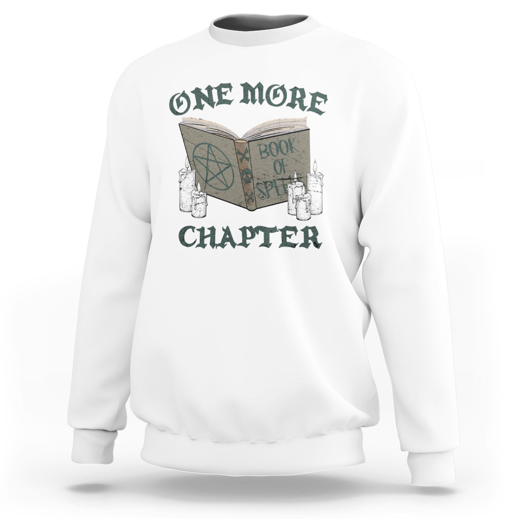 White sweatshirt with front graphic of an open book, candles, and “ONE MORE CHAPTER”