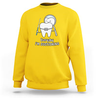 Yellow sweatshirt with cartoon dental character holding a suction tool graphic