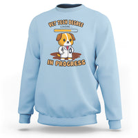 Light blue vet tech degree sweatshirt with cartoon dog and “in progress” graphic on chest