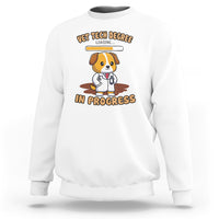White vet tech degree sweatshirt with cartoon dog and “in progress” graphic on chest