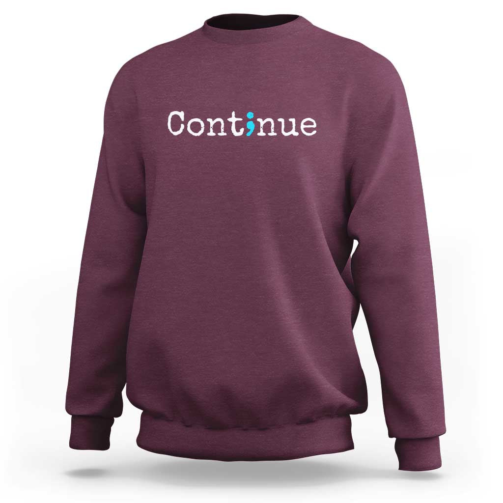 Maroon crewneck sweatshirt with white “Continue” text and green semicolon graphic