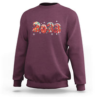 Maroon crewneck sweatshirt with colorful 2023 graphic and festive snowflake accents