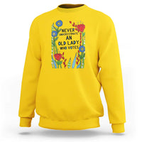 Daisy yellow crewneck sweatshirt with “Never Underestimate an Old Lady Who Votes” graphic