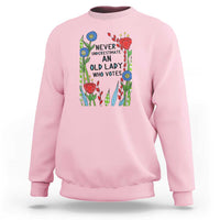 Light pink crewneck sweatshirt with “Never Underestimate an Old Lady Who Votes” graphic