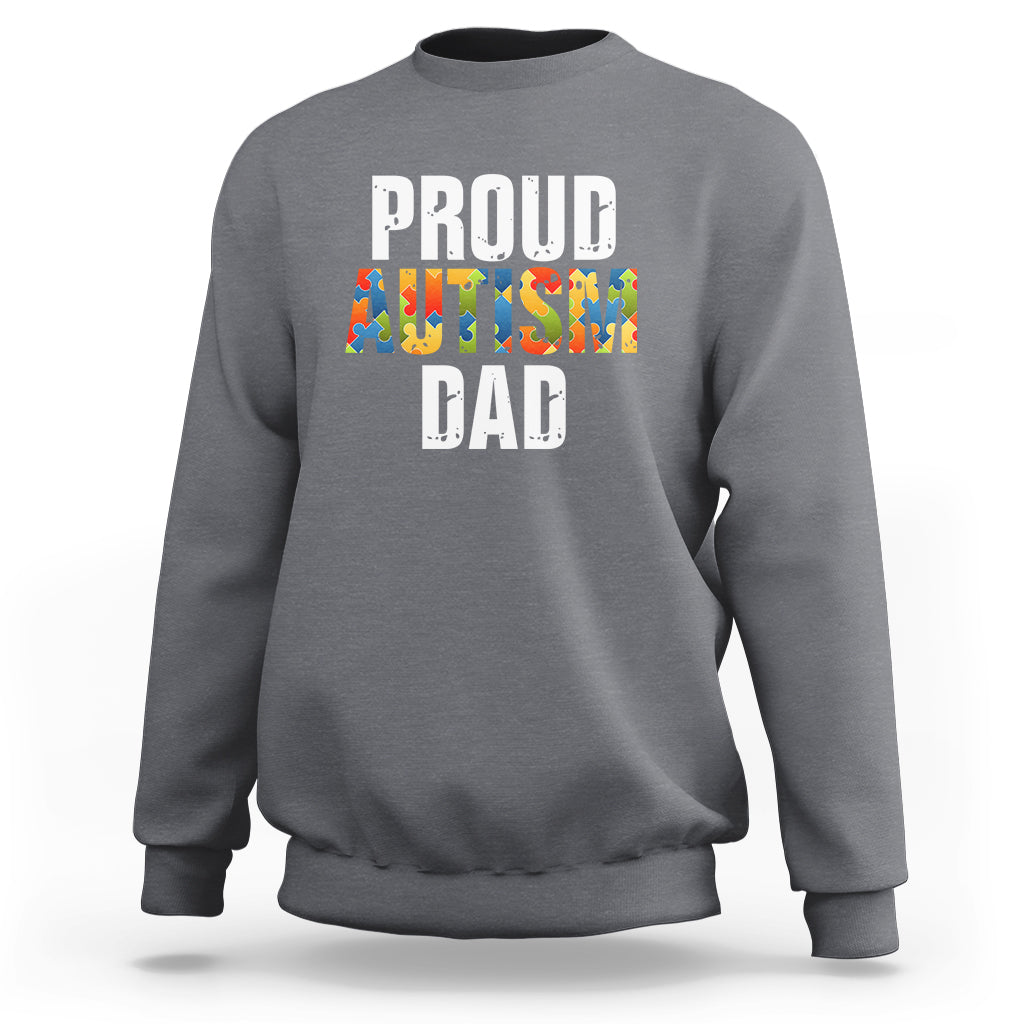 Dark heather gray sweatshirt with front text “PROUD AUTISM DAD” and colorful puzzle graphic.