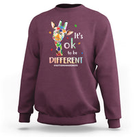Maroon crewneck sweatshirt with colorful giraffe graphic and “It’s ok to be different” print