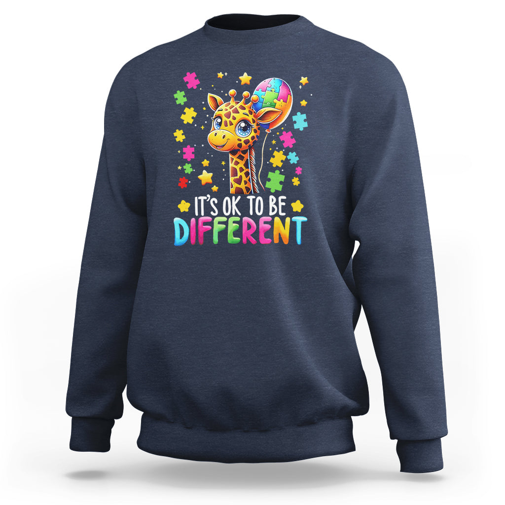 Blue crewneck sweatshirt with colorful giraffe puzzle graphic and “It’s ok to be different” text