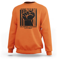 Orange crewneck sweatshirt with black Juneteenth-style fist graphic on the front