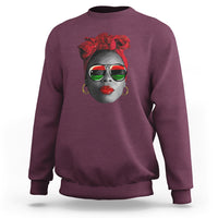 Women’s maroon sweatshirt with red patterned face graphic at chest