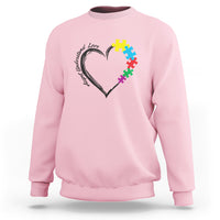 Light pink autism awareness sweatshirt with heart-and-puzzle graphic on chest.