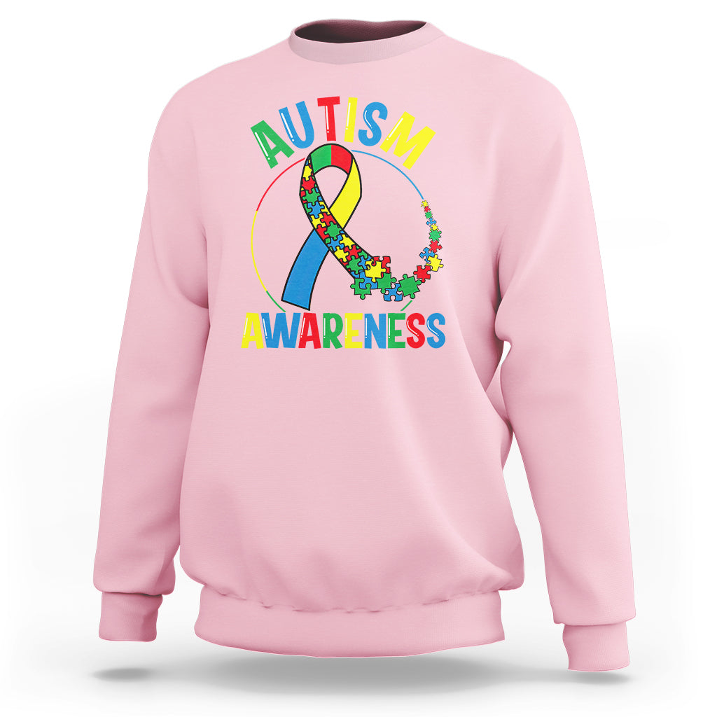 Light pink autism awareness sweatshirt with multicolor puzzle ribbon graphic on front