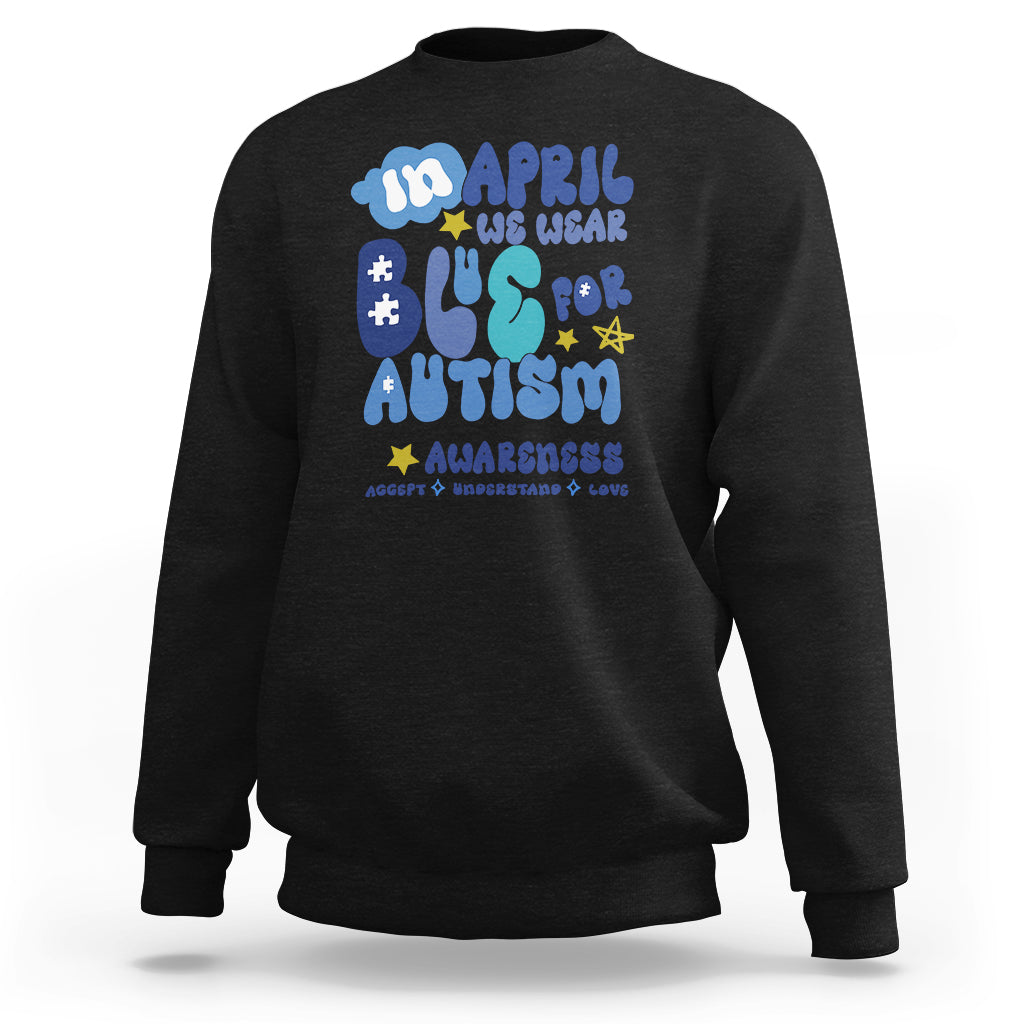 Black autism awareness sweatshirt with colorful “April we wear blue” graphic on chest