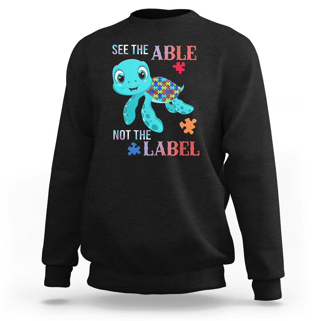 Black autism sweatshirt with cartoon turtle and puzzle-piece graphics, “See the Able, Not the Label”