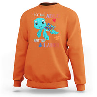 Orange autism sweatshirt with cartoon turtle and puzzle-piece graphics, “See the Able, Not the Label”