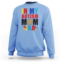 Light blue sweatshirt with colorful Autism Mom puzzle-piece graphic, crewneck long sleeves.